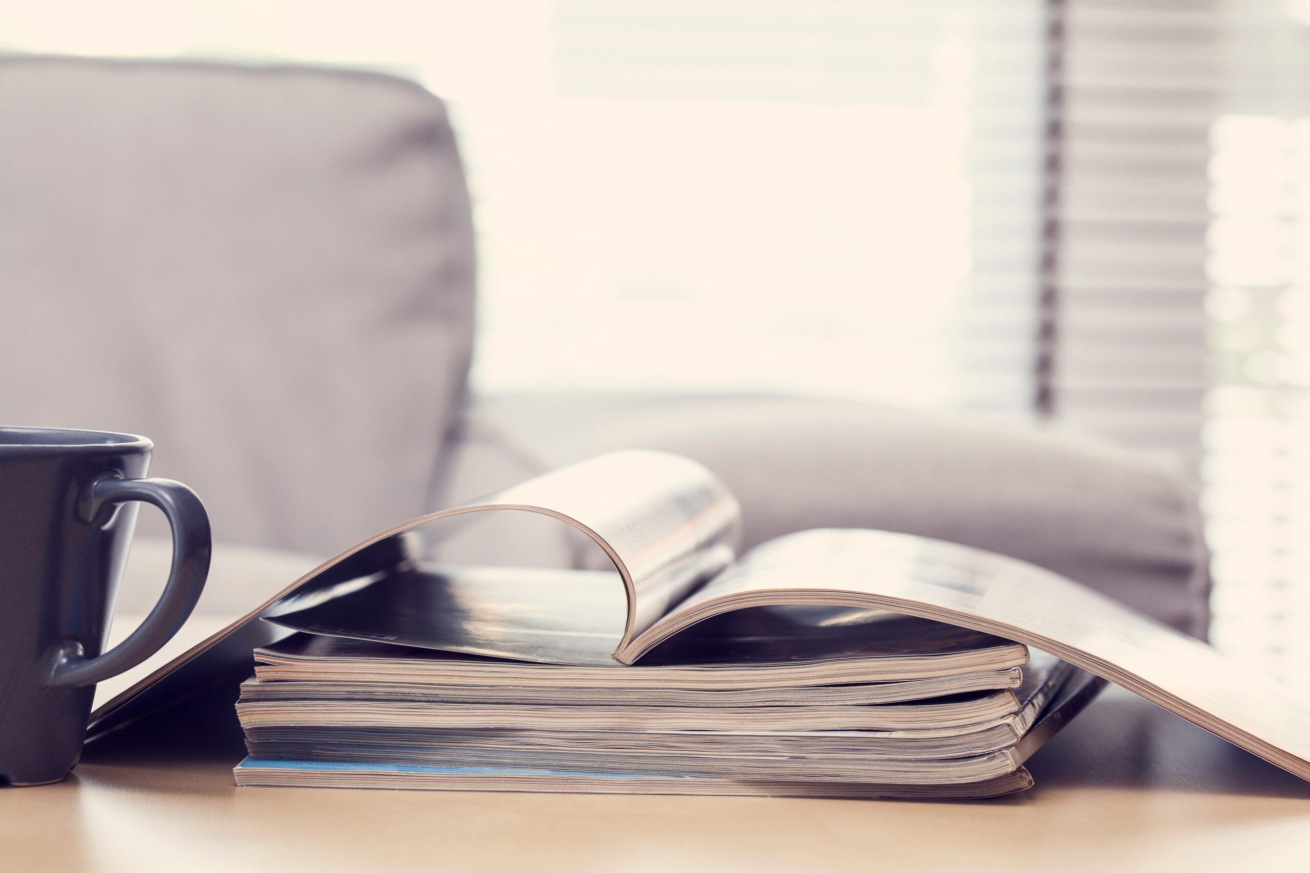 Magazine ouvert et tasse de café sur une table basse, ambiance salle d'attente
